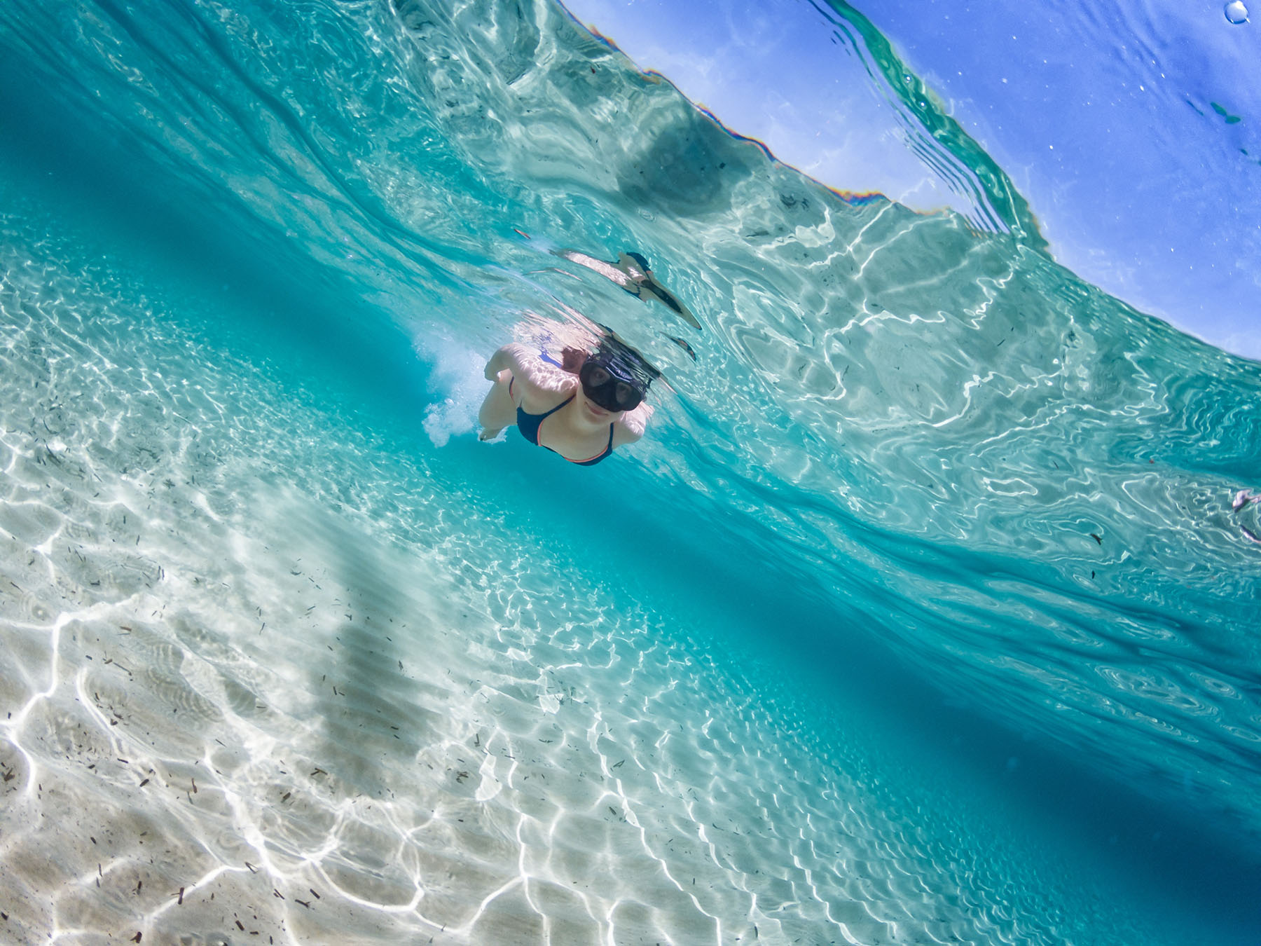 Caucasian woman making snorkeling in the Mediterranean Sea, Sardinia sea. Half underwater photography